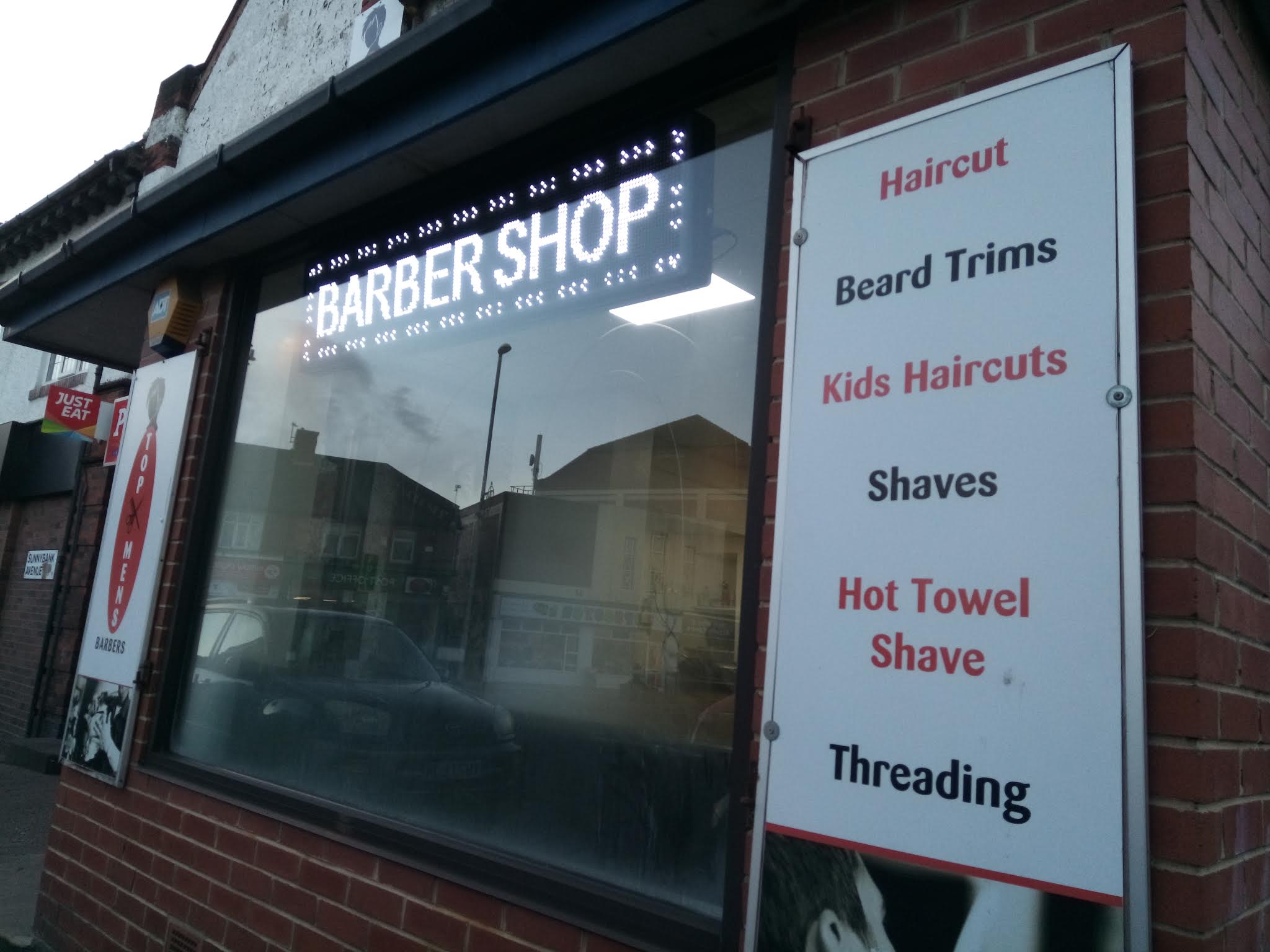 Haircuts, beard trims and hot towel shaves listed on the barbershop window
